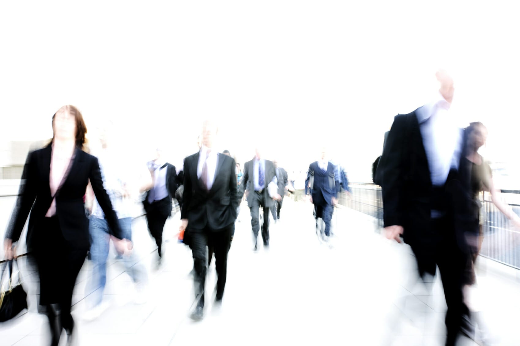 Blurred image of people walking in business suits.