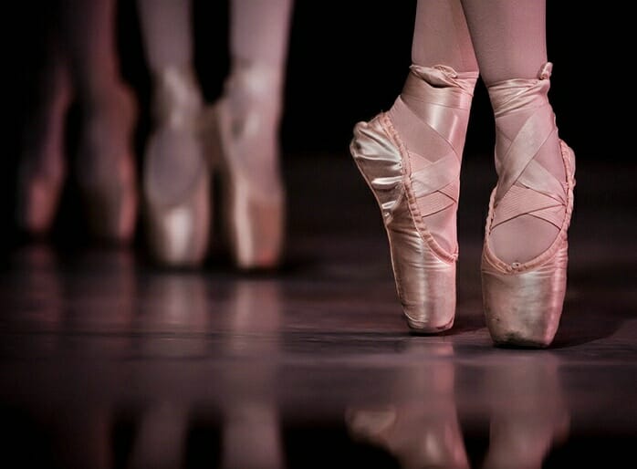 Feet in pink ballet shoes on toe point.