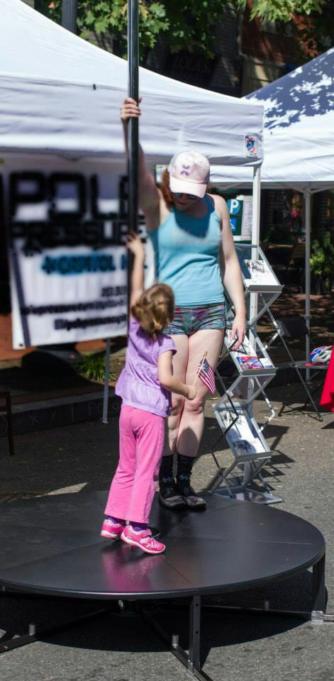 Adult and child play on an outdoor stage pole