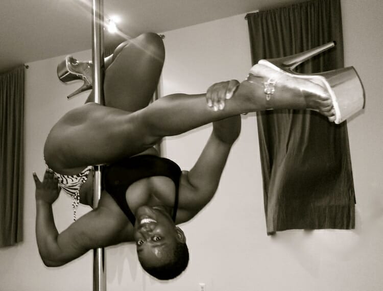 Pole dancer executes a modified Jade split on a pole.