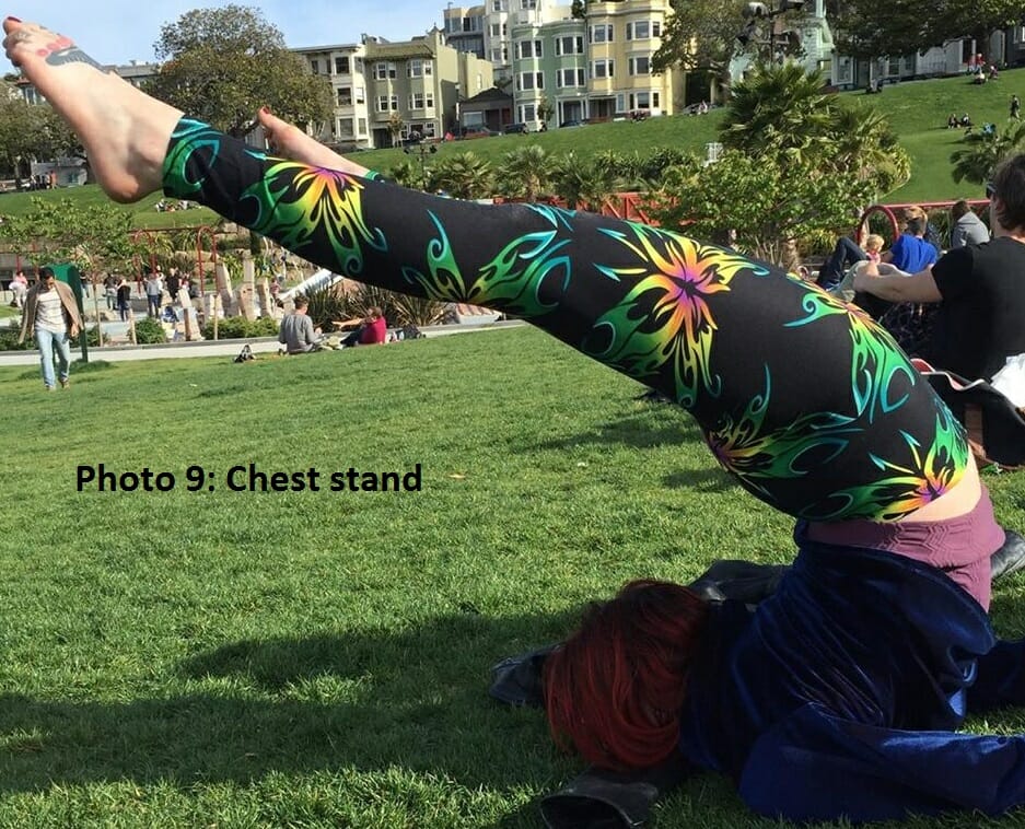 Acro person executes a chest stand in an outdoor park.