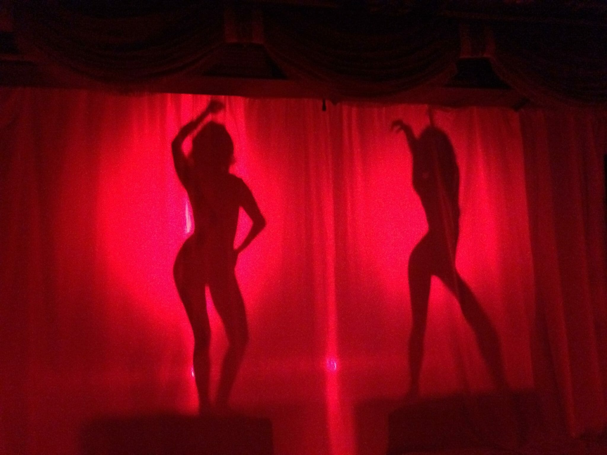 Silhouette of two apparent women against a red light.