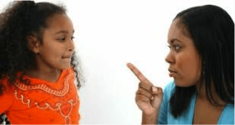 Two femme presenting individuals, one younger, one older, with the older one pointing a finger at the younger, on a white background.