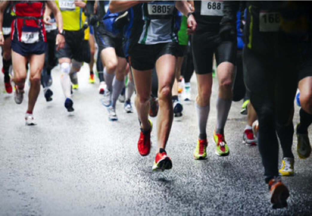 Image of runners in a road race taken from the torsos down.