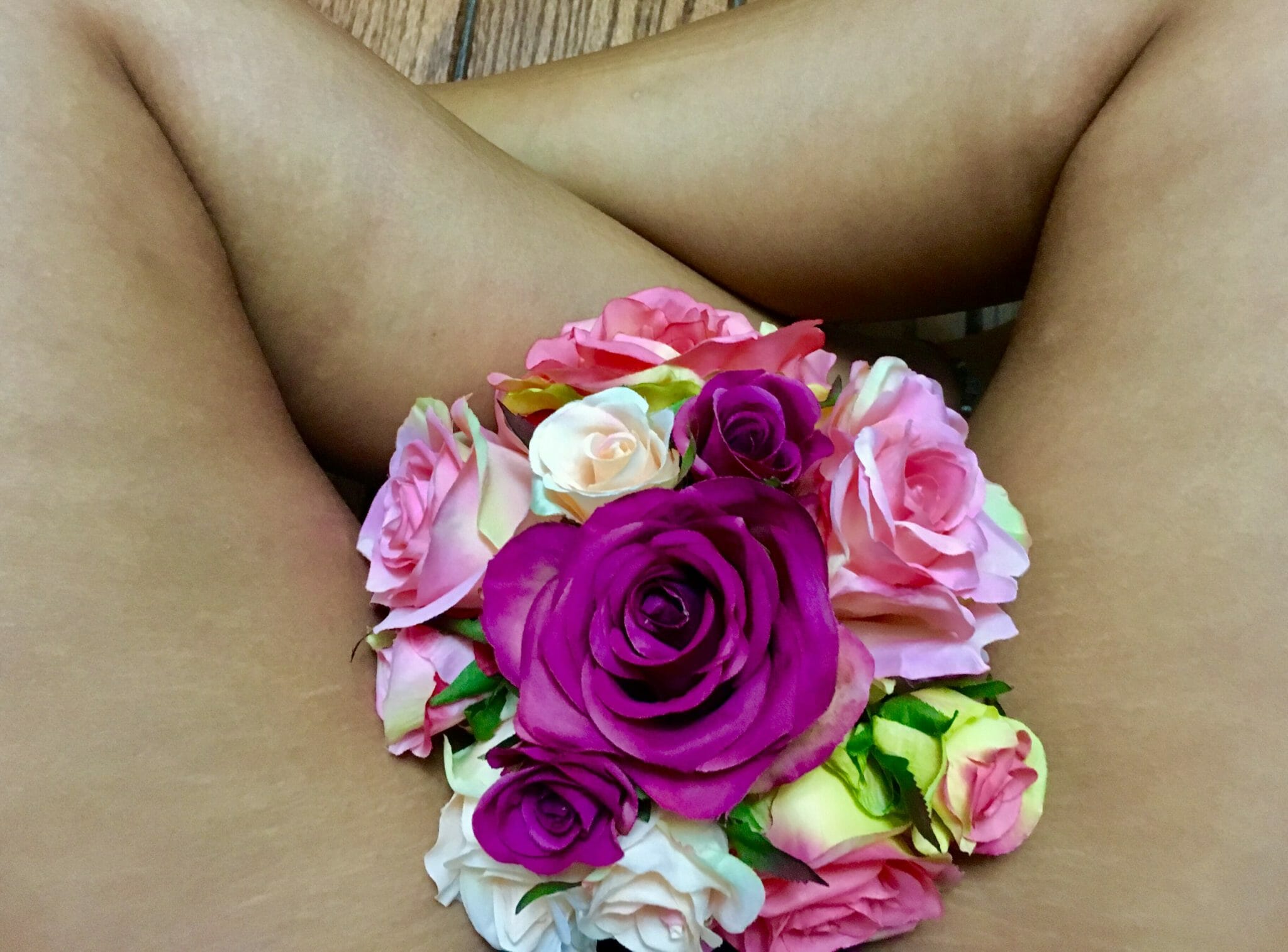 Individual sitting with crossed angles and boquet of flowers covering the crotch.