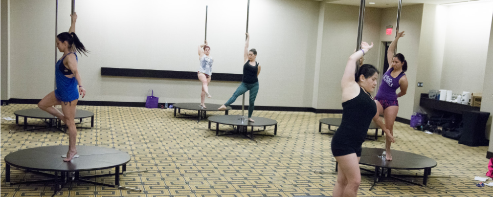 Students work on pirouettes during a workshop at PoleCon 2015