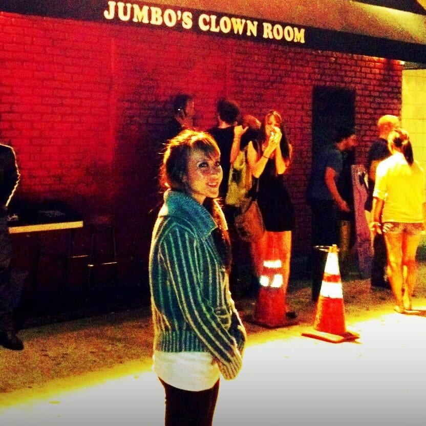 Individual smiles in front of wall sign: Jumbo's clown room