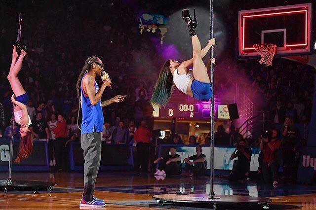 Snoop Dogg performs while watching his back-up pole dancer perform