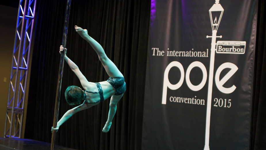 Pole dancer executing an iron-x on stage at PoleCon 2015