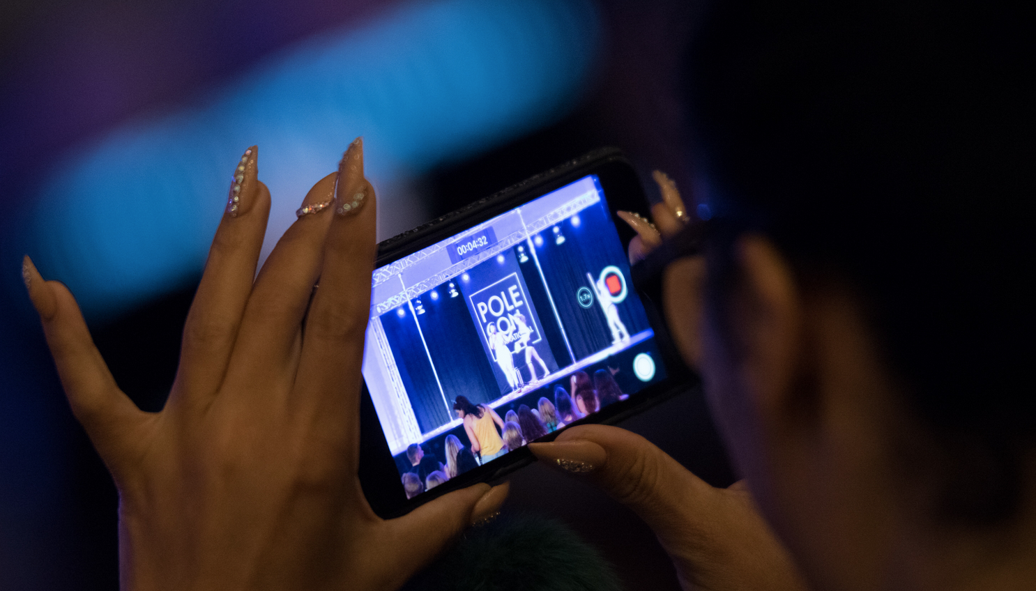 Individual watches the PoleCon show through a cellphone