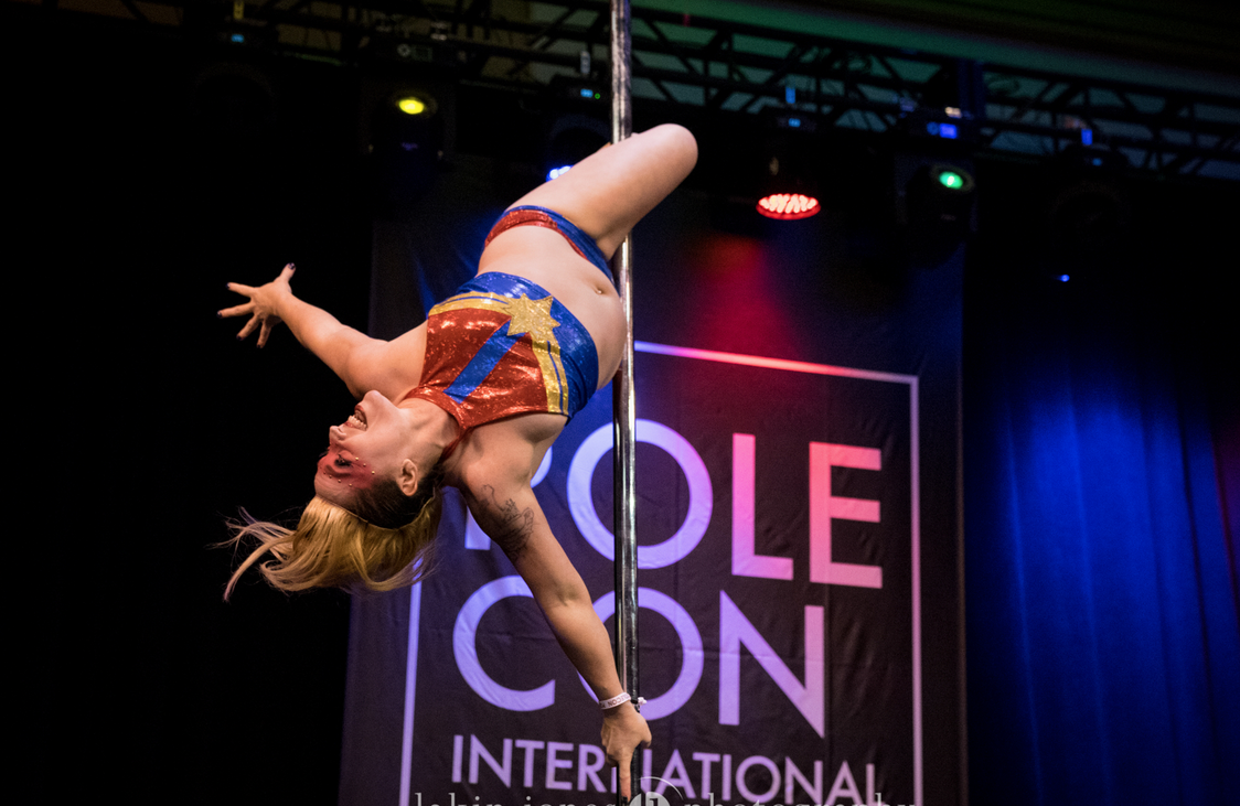 Pole Dancer on stage in a Gemini / outside leg hang