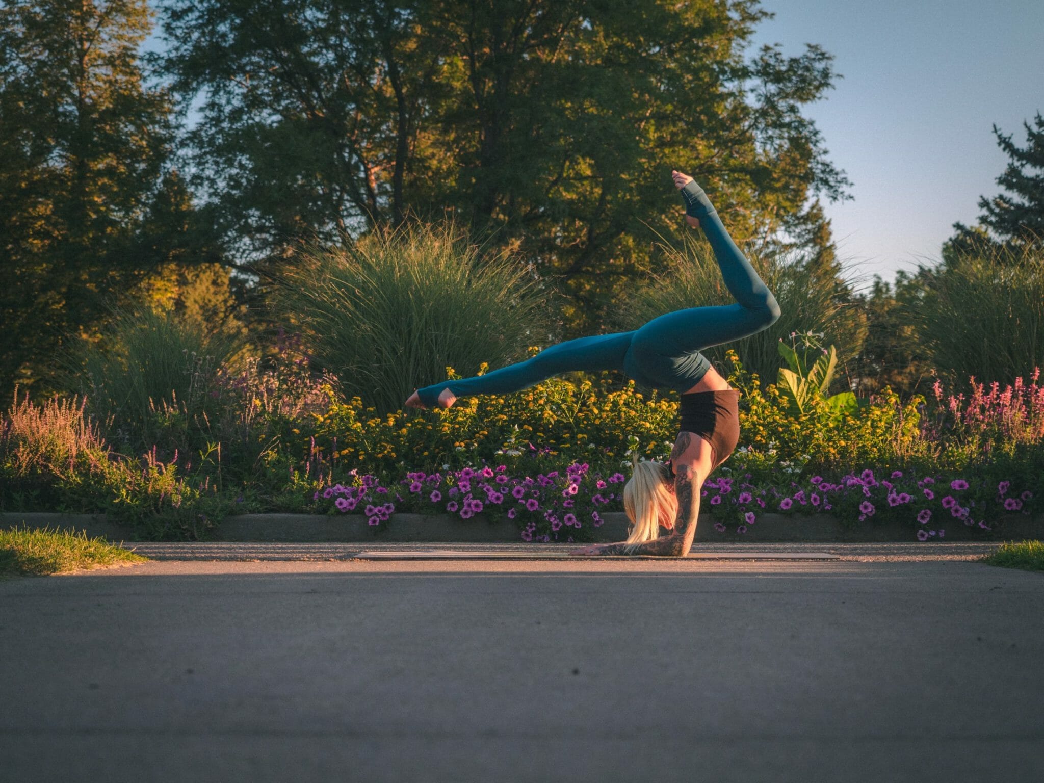 Athlete performs a forearm handstand in a garden setting