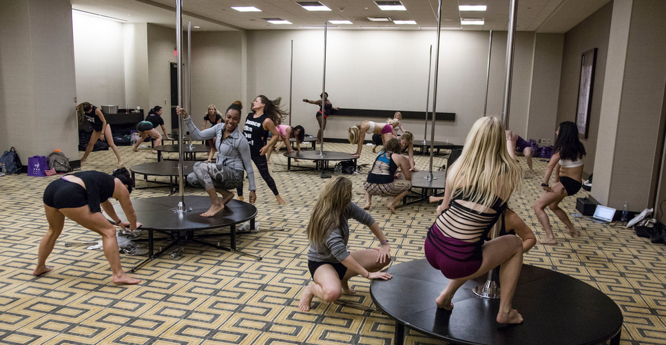 Students practice on stage poles during a workshop