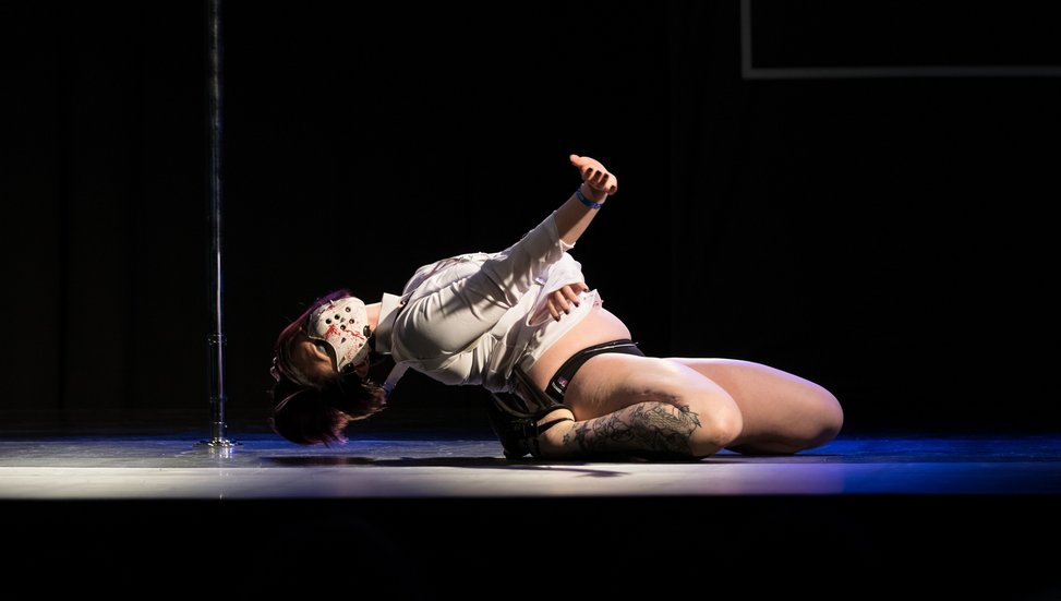 Jax Spenser leans back during floor work in a performance wearing a half-mask