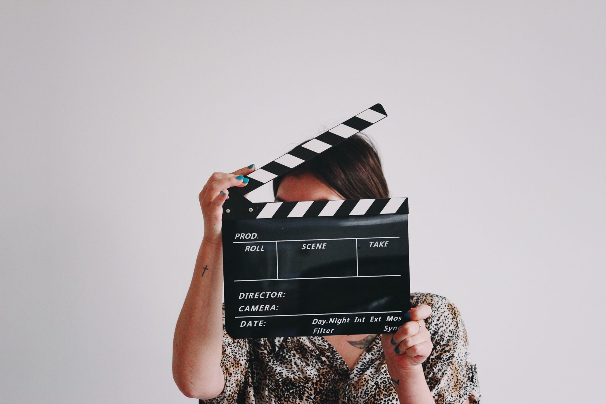 Individual hides behind a movie clapperboard.