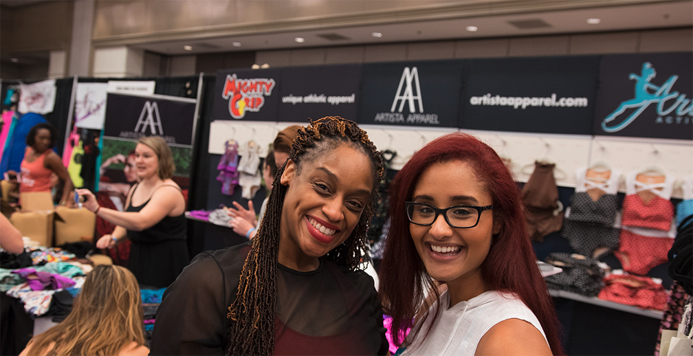 Attendees smile at the camera in front of vendor booth.