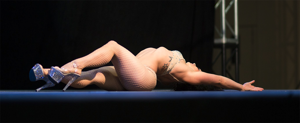 Image of dancer arched on the floor wearing white fishnets and stilettoes.