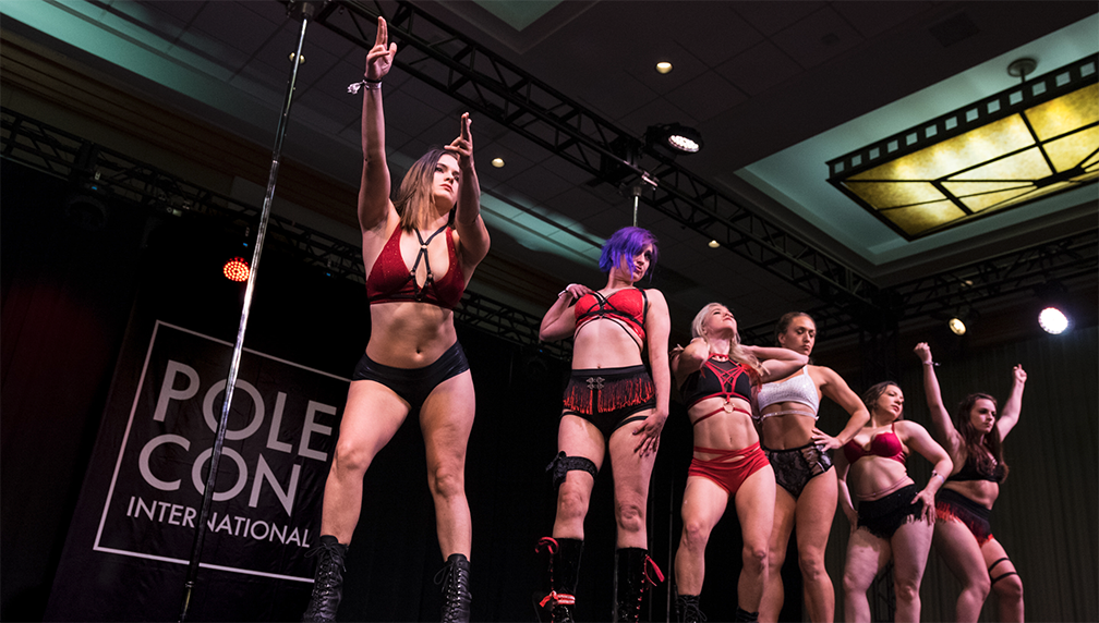 Dancers lined up at the front of the stage performing during the troupes and groups showcase.