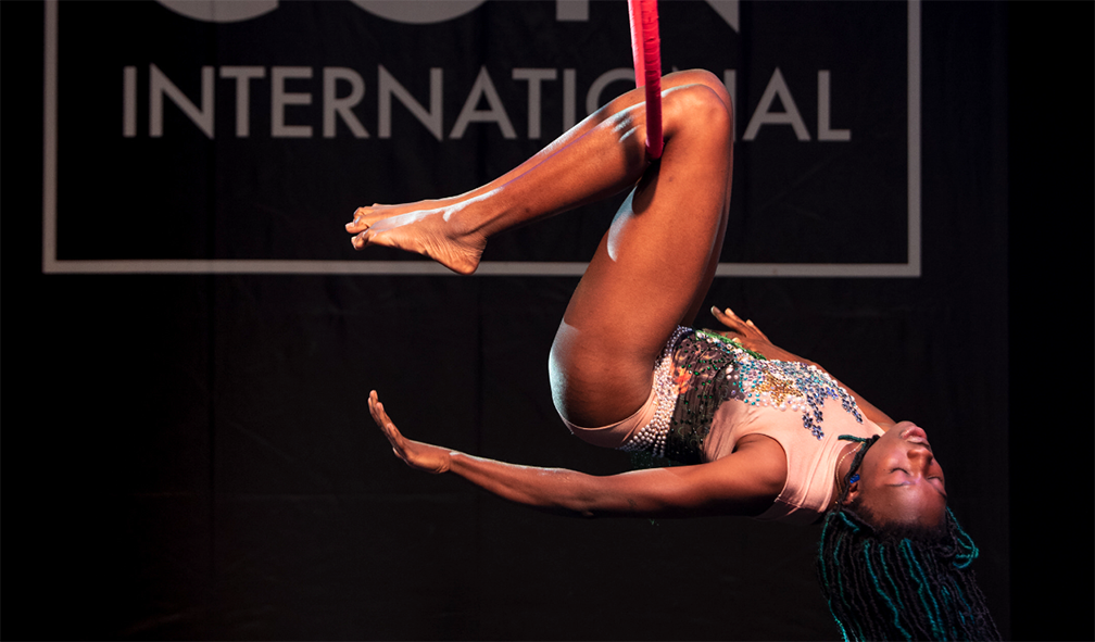 Performer dances on aerial hoop on stage.