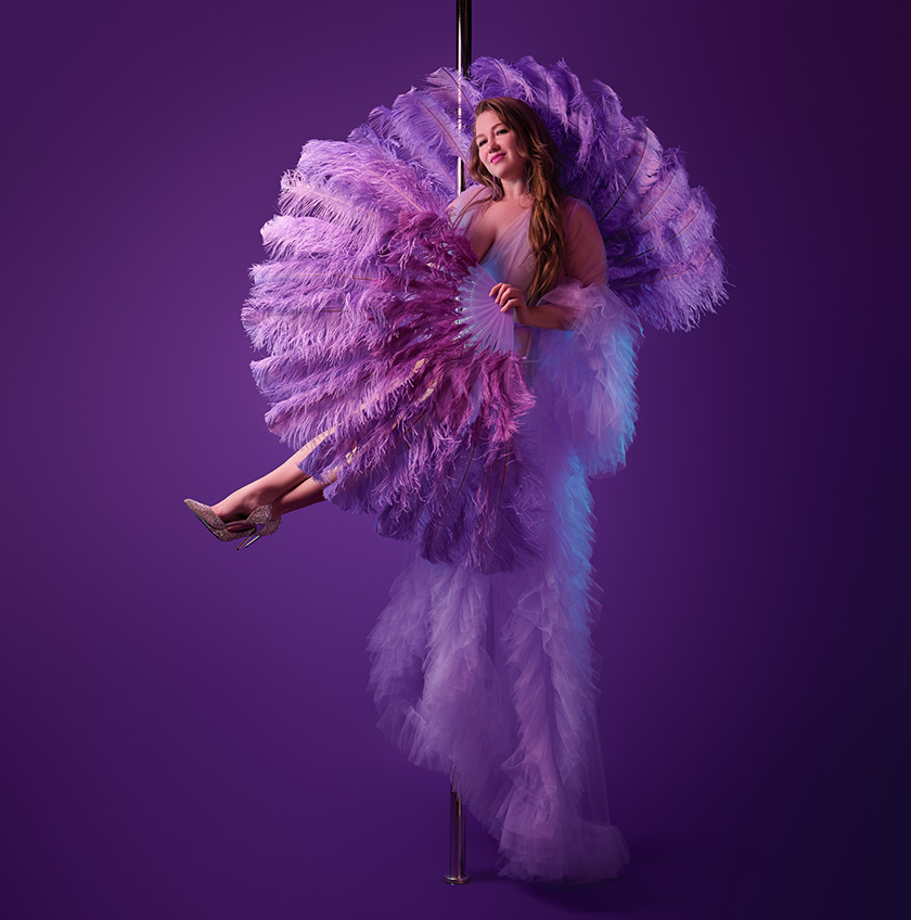 Pole dancer with feather fans in professional photoshoot.