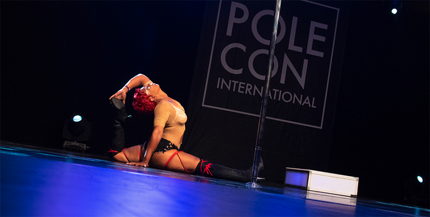 Pole dancer performs the splits during floorwork.