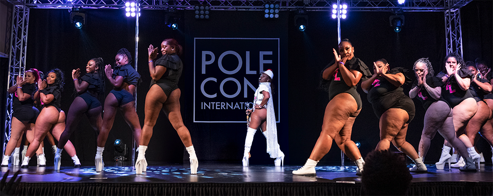 Pole dancing troupe performs on stage.
