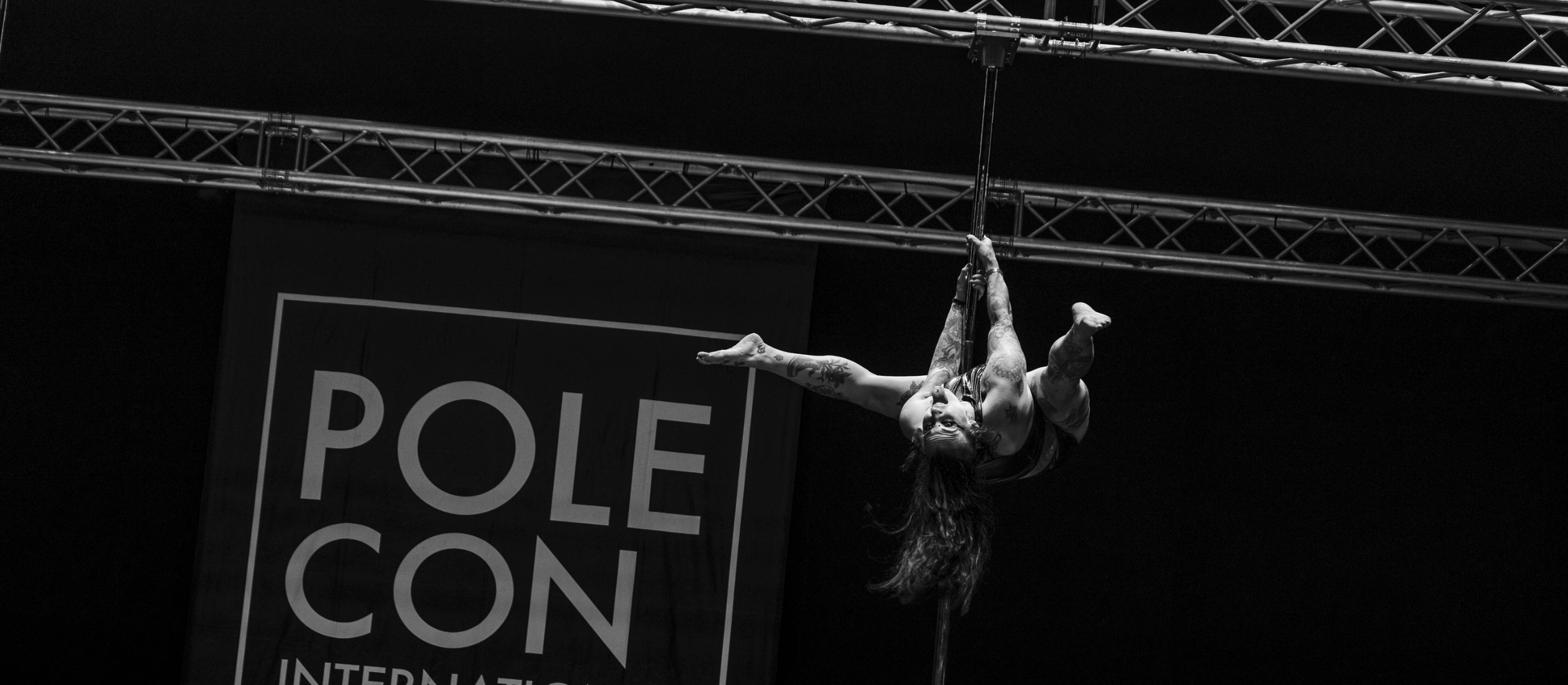 Casey Danzig does an inverted pole move on the PoleCon stage.