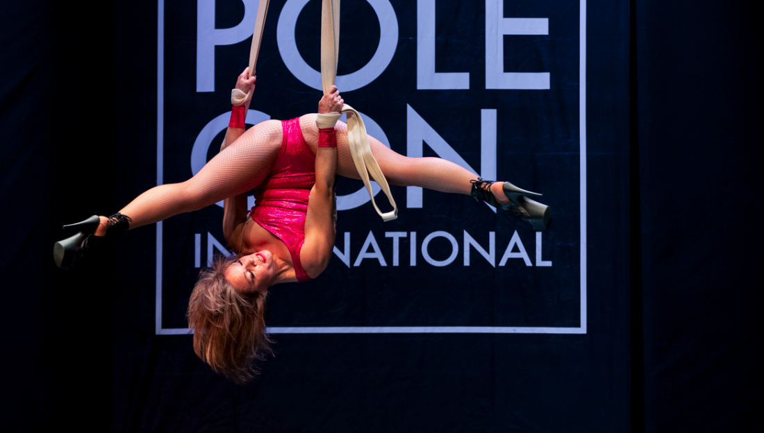 Dancer inverts using straps apparatus at PoleCon.