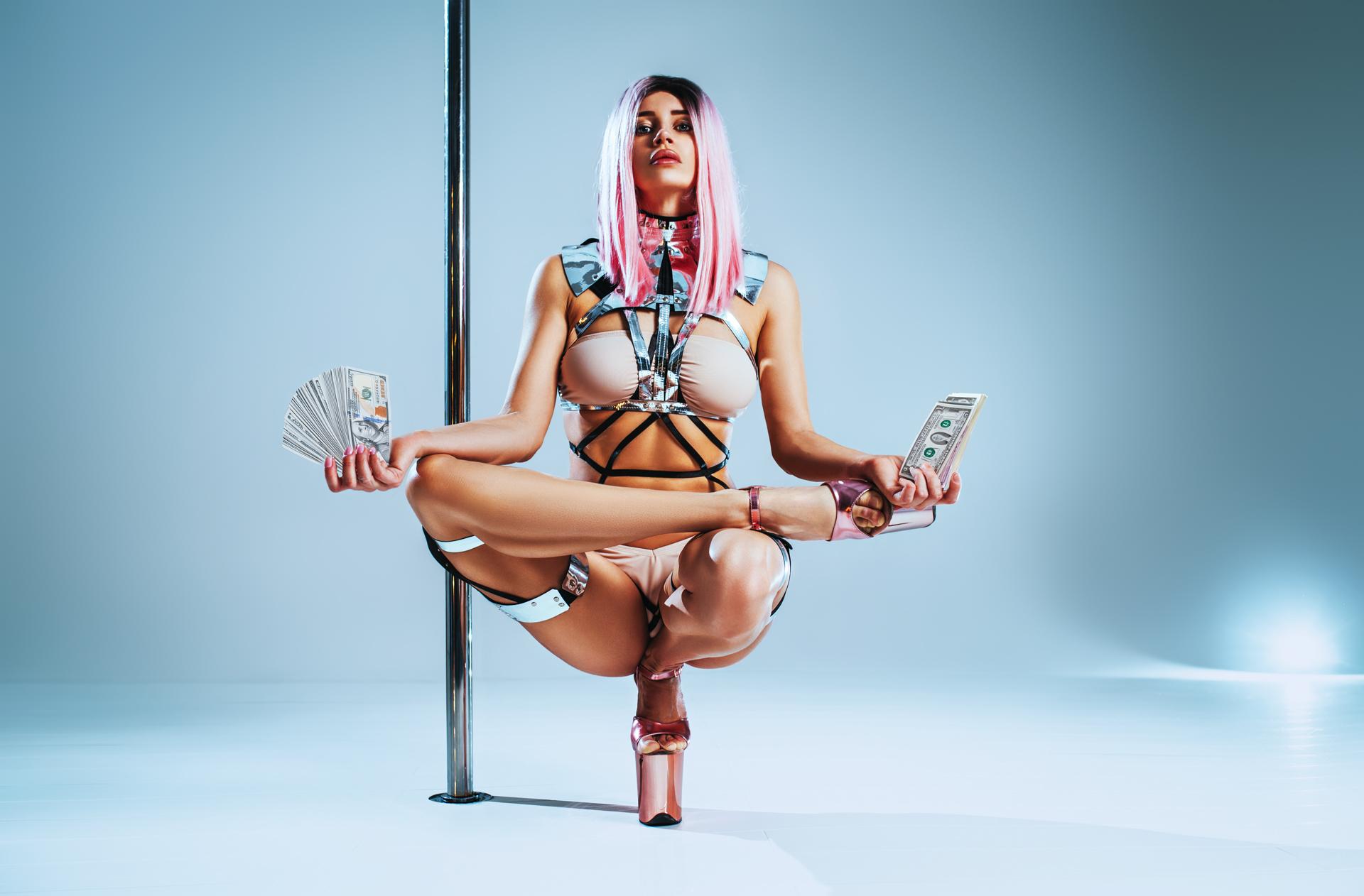 pole dancer sitting in lotus pose holding money